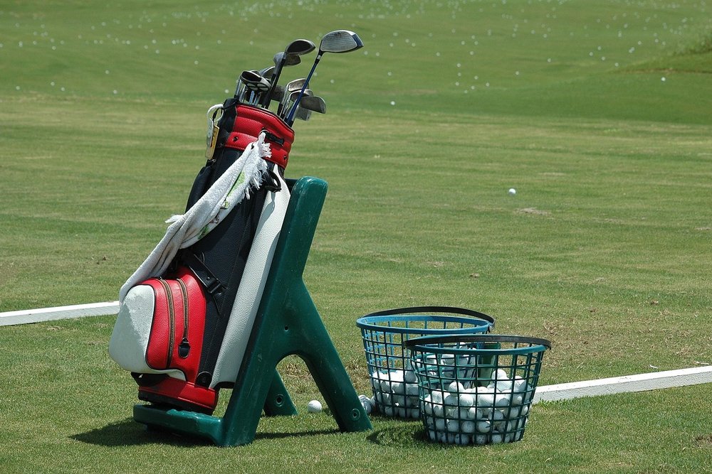 Golf bag on a stand at a driving range next to a basket of balls