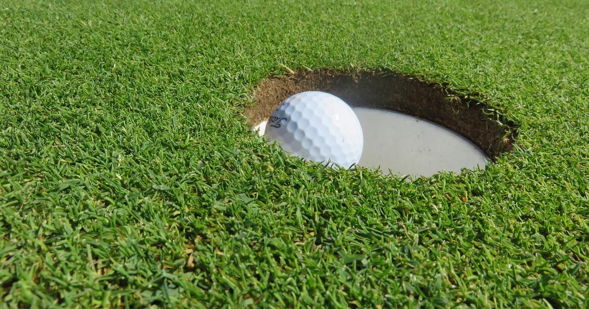 Golf ball on the lip of the hole on a putting green
