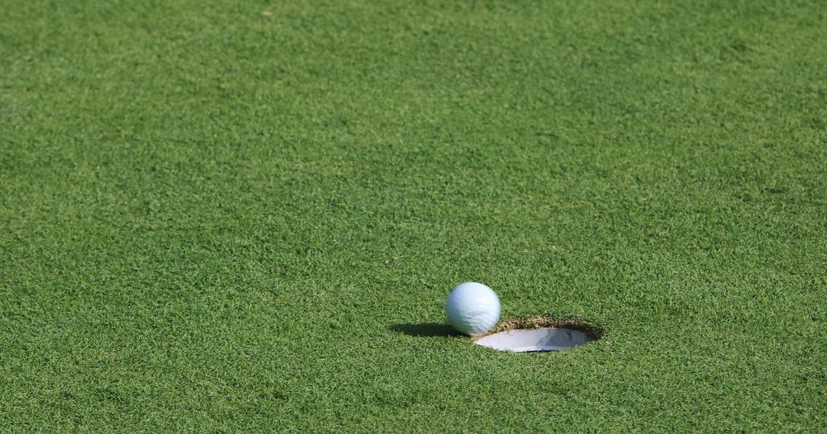 Golf ball resting just short of the hole on a green