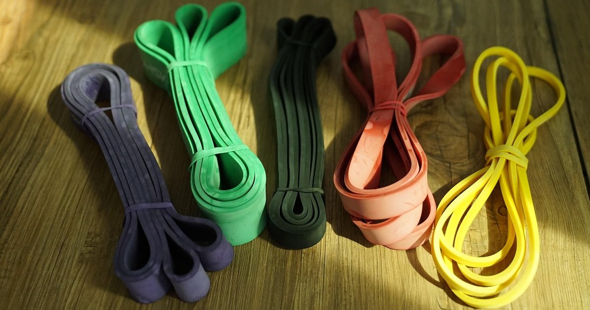 Five resistance bands of different strengths on a wooden floor