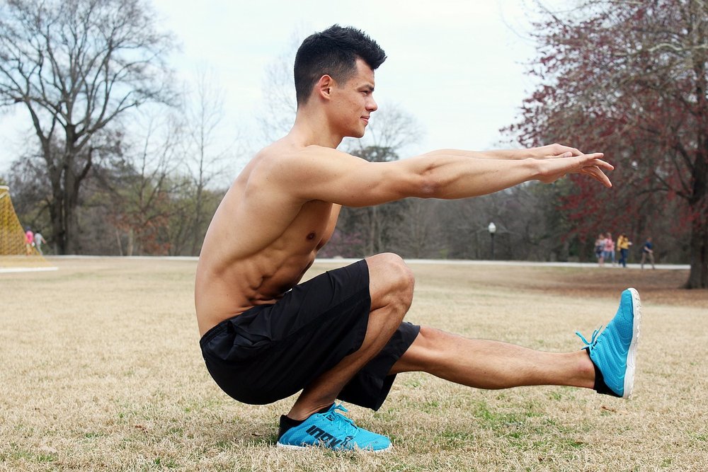 Man doing a single-leg squat outdoors with arms stretched forward