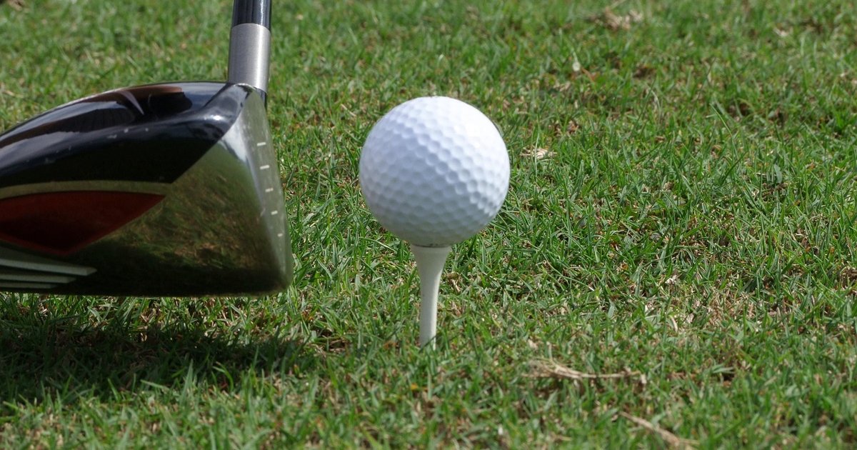 Driver set behind a ball on a wooden tee