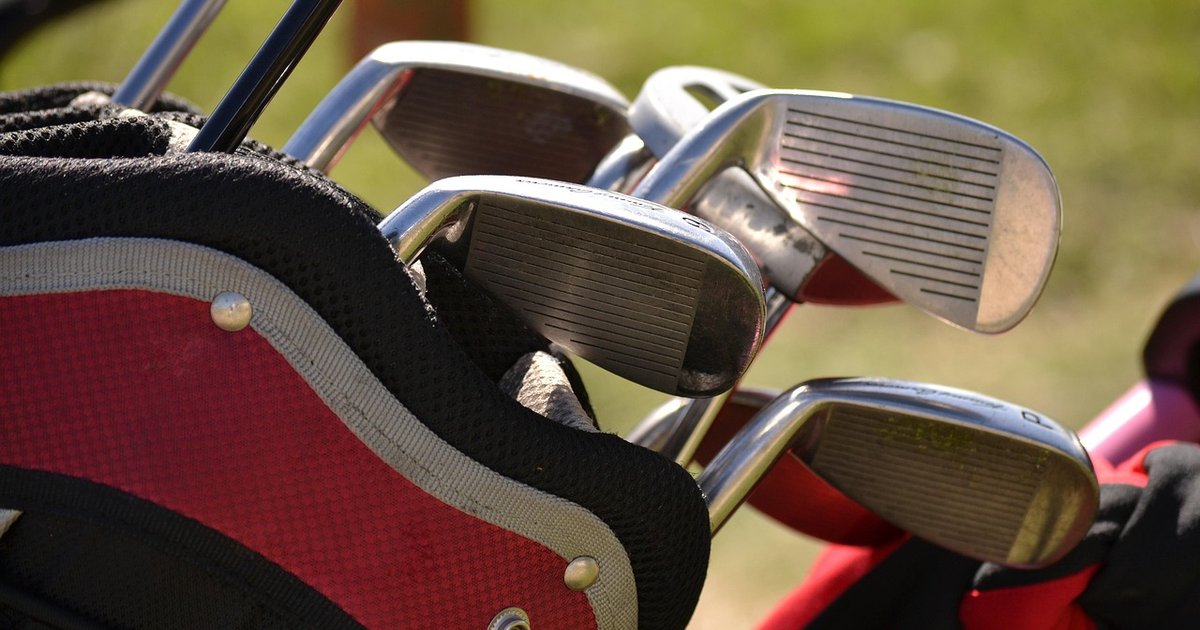 Irons with worn chrome heads in a red golf bag