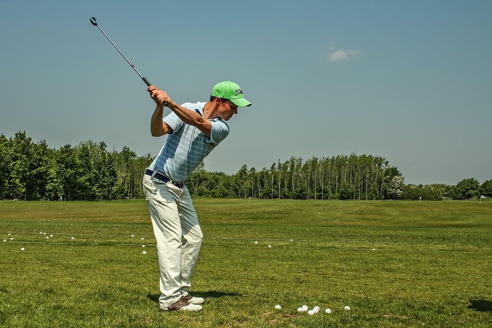 Golfer finishing a drive on an open fairway