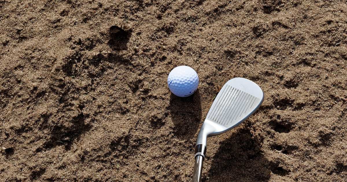 Wedge and golf ball in a sand bunker